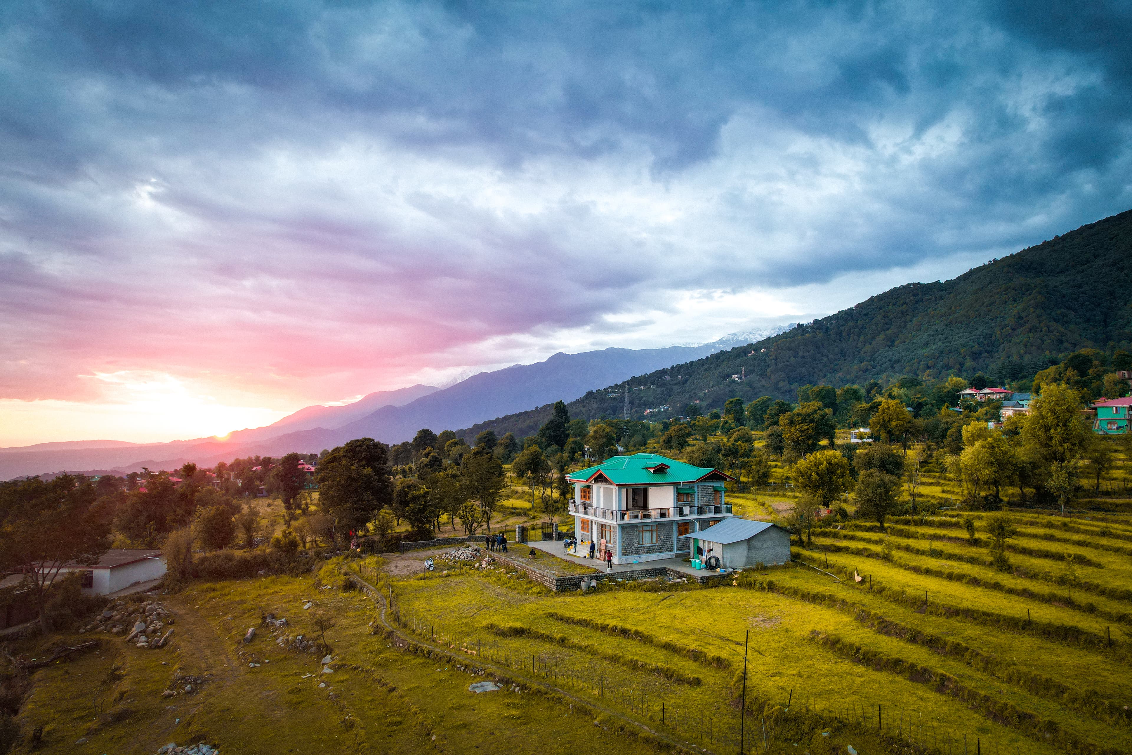 Aerial sunset view of rural landscape with green-roof house and terraced fields